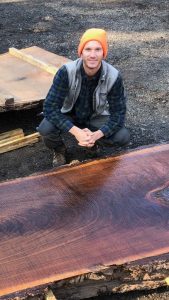 A man kneeling down next to a wooden table.